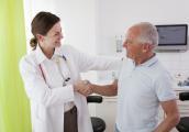 Ärztin gibt älterem Patienten im Behandlungszimmer die Hand.