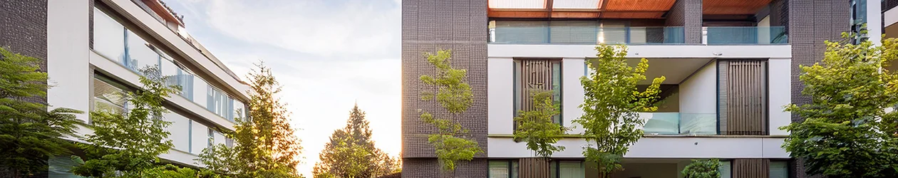 Eine moderne Wohnung in einer gehobenen Wohngegend vor blauem Himmel und hinter grünen Bäumen und Sträuchern