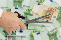 Hand mit Schere vor Euro-Geldscheinen