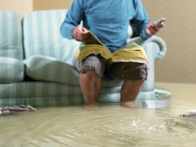 Mann auf Couch bei Hochwasser