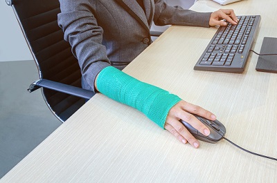 Frau mit gebrochenem Arm im Büro