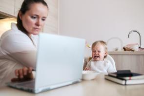 Mutter füttert Kind im Homeoffice