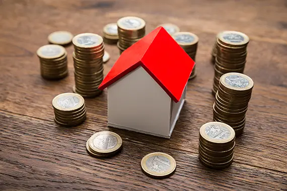 zu unseren Baufinanzierungs-Ratgebern Modellhaus mit Münzen