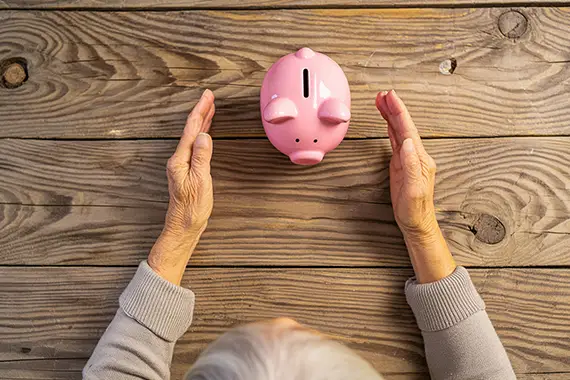 zu unseren Geldanlage-Ratgebern Eine ältere Person mit einem Sparschwein