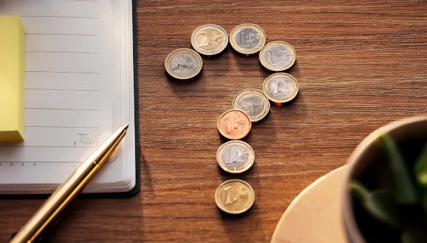 Wann lohnt sich eine vorzeitige Ablöse des Kredits? Ein Fragezeichen aus Münzen auf einem Tisch