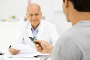 Ein Patient reicht seinem Arzt eine Kreditkarte.